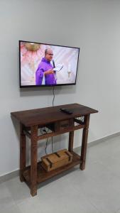 einen TV an einer Wand mit einem Holztisch und einem TV in der Unterkunft Apart-hotel St° Antônio de Pádua in Santo Antônio de Pádua