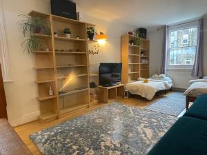 a living room with a bed and a television at 10 min to The Heart of London - Zone 2 - Charming 2 bed Apartment in London