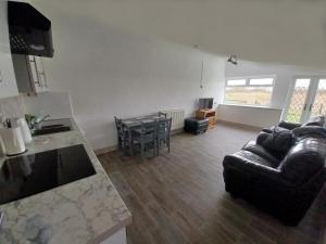 ein Wohnzimmer mit einer Ledercouch und einem Tisch in der Unterkunft Redhouse Farm Cottage the most dog friendly place Ive ever stayed in Withernsea