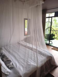 uma cama com uma rede mosquiteira branca num quarto em White Elephant Ella em Ella