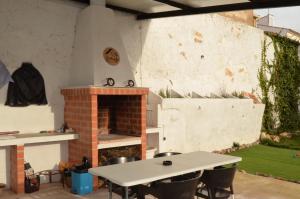 a outdoor kitchen with a table and a fireplace at La Antigua, casa céntrica, amplio patio y barbacoa in Campillo de Altobuey