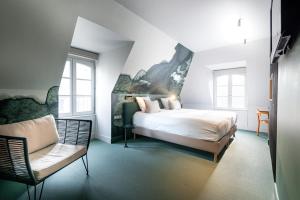 ein weißes Schlafzimmer mit einem Bett und einem Stuhl in der Unterkunft Hôtel de la Cité in Saint-Malo