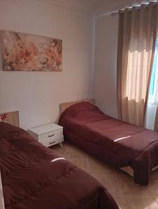 een slaapkamer met 2 bedden en een raam bij Bel appartement proche de la mer Hammamet in Hammamet