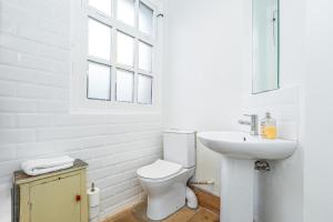 a white bathroom with a toilet and a sink at Unique Detached House wPrivate Courtyard, London in London