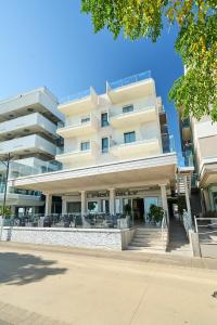 un gran edificio con mesas y sillas delante de él en Hotel Piccadilly, en Bellaria-Igea Marina