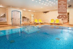 una piscina con sillas y sillas amarillas en una habitación en "Viktoria Apartments" - Annehmlichkeiten von 4-Sterne Familien-und Wellnesshotel Viktoria können mitgenutzt werden, en Oberstdorf