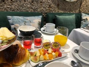 a table with a plate of food with fruit on it at Trovador Guest House in Guimarães