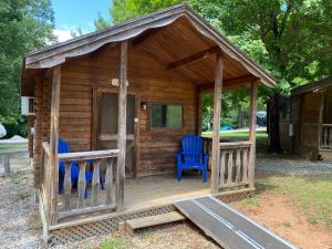 Cabaña de madera con 2 sillas azules en el porche en Poolside Rustic Cabin with Amazing Views, en Salisbury