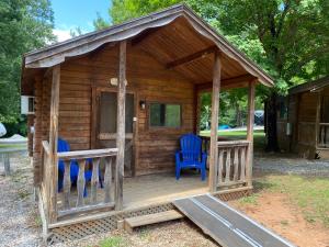 a wooden cabin with two blue chairs on the porch at Poolside Rustic Cabin with Amazing Views in Salisbury