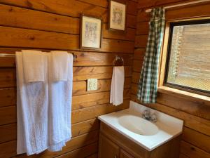 y baño con lavabo, espejo y toallas. en Poolside Rustic Cabin with Amazing Views, en Salisbury