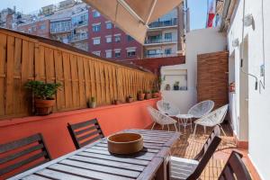 eine Terrasse mit einem Holztisch und Stühlen auf dem Balkon in der Unterkunft Eixample 5 in Barcelona