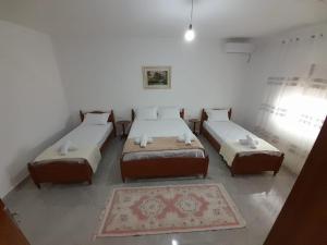 Habitación con 3 camas y alfombra. en Villa Besart en Berat