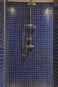 a blue tiled bathroom with a shower with a hose at Villa Rustica in Sorico