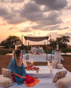 a woman sitting on a couch in front of a table at Jaisalmer Sam Sand Dunes Luxury Camps in Jaisalmer