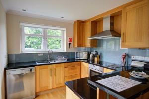 a kitchen with wooden cabinets and a black counter top at No1 The Links Apartment, Brora in Brora