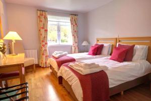 a bedroom with two beds and a desk and a window at No1 The Links Apartment, Brora in Brora