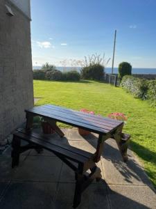 a wooden picnic table sitting on a sidewalk next to a field at No1 The Links Apartment, Brora in Brora