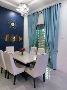 une salle à manger avec une table et des chaises blanches dans l'établissement Puteri Homestay Sg Petani, à Sungai Petani