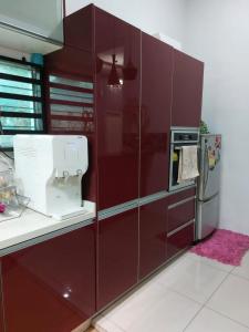 uma cozinha vermelha com um misturador e um frigorífico em Puteri Homestay Sg Petani em Sungai Petani
