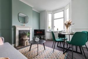 a living room with a table and green chairs at Perry Place - Forest Hill- 3 bed house in London