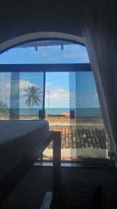 a room with a view of a beach and a palm tree at hostel quintal da sereia in Salvador