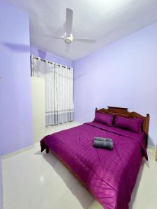 een slaapkamer met een paars bed en een ventilator bij Homestay Kuala Terengganu Gong Badak in Kuala Terengganu