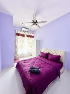 een slaapkamer met een paars bed en een plafondventilator bij Homestay Kuala Terengganu Gong Badak in Kuala Terengganu