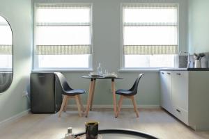 - une cuisine avec 2 chaises, une table et 2 fenêtres dans l'établissement Trendy Studio near Notting Hill, à Londres