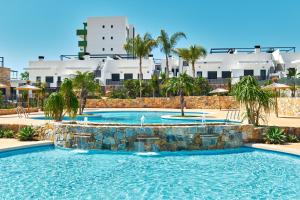 a swimming pool with a resort in the background at Sunshine in Pilar de la Horadada