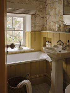 baño con bañera, lavabo y ventana en Plum House en Haslemere