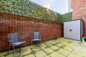 dwa krzesła siedzące na patio obok ściany z cegły w obiekcie GuestReady - Modern lodge with garden w Londynie
