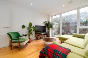 a living room with a couch and a tv at GuestReady - Modern lodge with garden in London