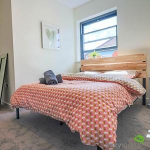 a bedroom with a bed with an orange and white comforter at Cambridge Mews in Cleethorpes
