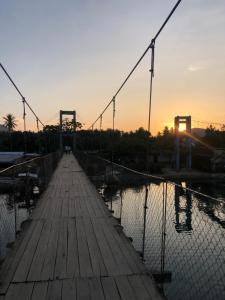 a bridge over a body of water at sunset at Bucana Beach Camp in El Nido