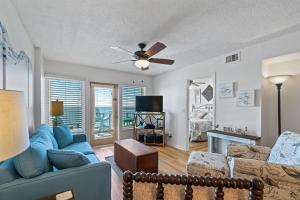 een woonkamer met een blauwe bank en een plafondventilator bij Boardwalk 783 in Gulf Shores