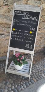 a chalkboard sign with a potted plant on a stand at Residenza Erbaluna in Oggebbio