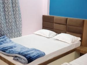 Bett mit weißen Kissen und blauer Decke in der Unterkunft Shridham Homestay in Ujjain