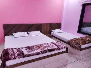 2 Betten in einem Zimmer mit rosa Wänden in der Unterkunft Shridham Homestay in Ujjain
