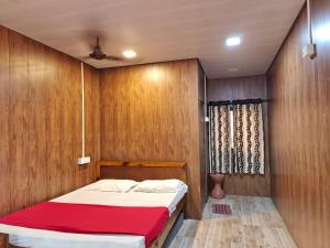 a bedroom with wooden walls and a bed with a red blanket at Iora Cottages in Alibaug