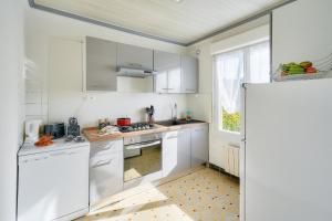 a white kitchen with white cabinets and a window at Cocon apaisant pour un sejour pres de la plage in Le Guilvinec