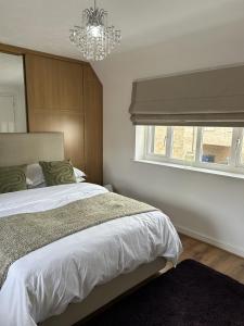 a bedroom with a bed with a chandelier and a window at Stylish house centrally located in Bury Saint Edmunds