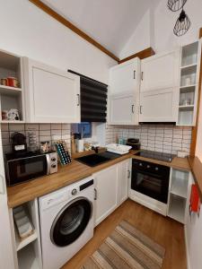 a kitchen with white cabinets and a washing machine at Casa Vale do Rio in Penacova