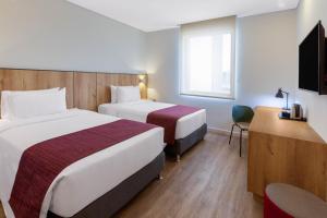 a hotel room with two beds and a television at Hotel Distrito ZF By OxoHotel in Bogotá