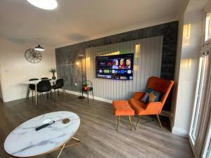 uma sala de estar com um sofá, uma mesa e uma televisão em Stylish 3-Bed House with Free Parking & Netflix by HP Accommodation em Northampton
