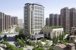 a large white building in a city with tall buildings at Pullman Taiyuan in Taiyuan