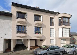 a building with two cars parked in front of it at Résidence Costallat in Bagnères-de-Bigorre