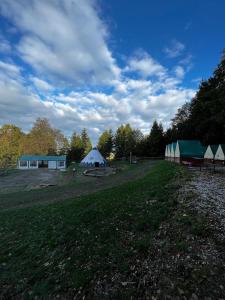 un campo con una tienda, un edificio y árboles en Ubytování na Horečky Ranči, en Nový Jičín