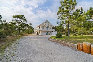 uma grande casa branca numa estrada de cascalho em Selah Cottage em Gulf Shores