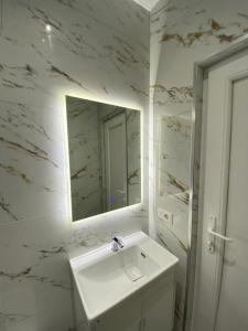a white bathroom with a sink and a mirror at Tirana Center Apartaments in Tirana