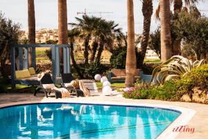 una piscina in un resort con palme di Gozo Dream with Heated Indoor Pool and an Outdoor Pool a Għarb
